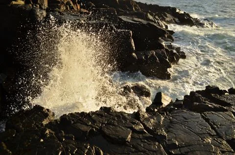 Waves splashing on the rocks on sunset Stock Photos