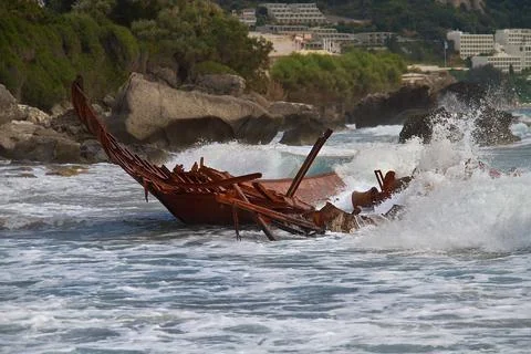 Waves splashing on the rusty wreck of a broken, stranded fishing boat Stock Photos