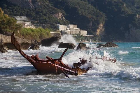 Waves splashing on the rusty wreck of a stranded ship Stock Photos