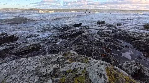Waves splashing slow motion onto rocky eroded coastal shoreline Stock Footage 325720543