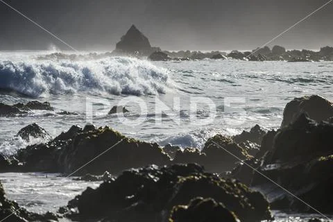 Waves splashing as they break close to shore and rugged rocks along the South co Stock Photos