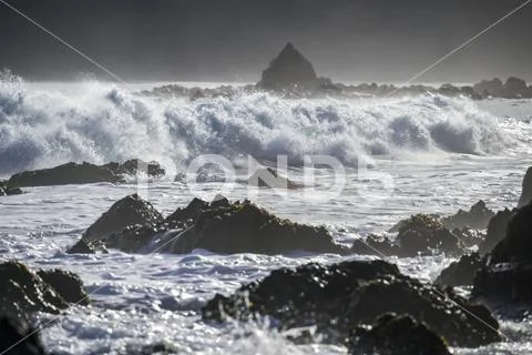Waves splashing as they break close to shore and rugged rocks along the South co Stock Photos