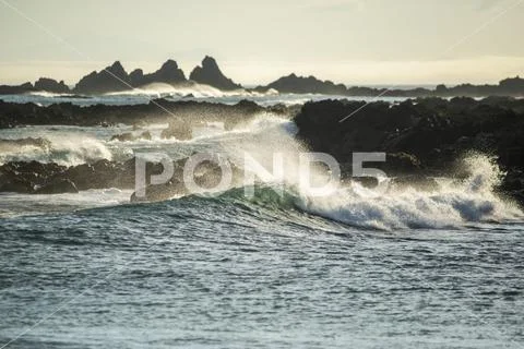 Waves splashing as they break close to shore and rugged rocks along the South co Stock Photos