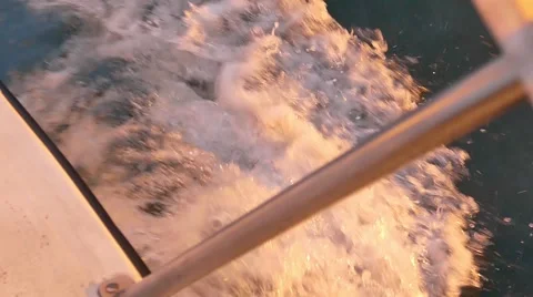 Waves spray from the side of a sailboat at sunset Vidéo 59803178