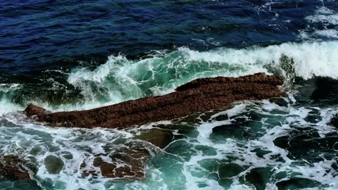Waves striking jagged reef in open ocean. Sea crashing against rough textured Stock Footage 320399017