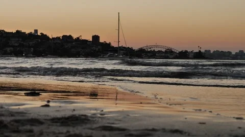 Waves at sunset with Sydney harbour bridge in distance slow motion 4K Stock Footage 270504705