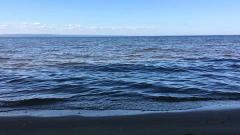 Waves, surf on the sandy beach. A view of the city in the distance on the Stock Footage 115795071