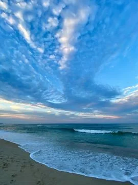 Waves, surf,  sky and clouds at dusk Stock Photos