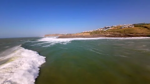 Waves surge over rocks, creating foam under bright sunlight Видео 346369226