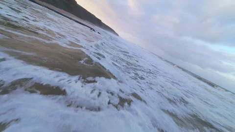 Waves surge over sand, spraying foam under cloudy sky Stock Footage 344673274
