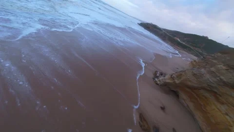 Waves surge over sandy beach near steep cliffs Stock Footage 344674946
