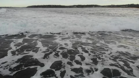 Waves swah fast while a drone flies past, low to the water Stock Footage 135646842