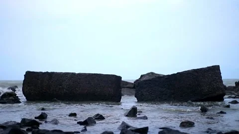 Waves sweeping the shoreline against a background of black square stones Stock Footage 262365554