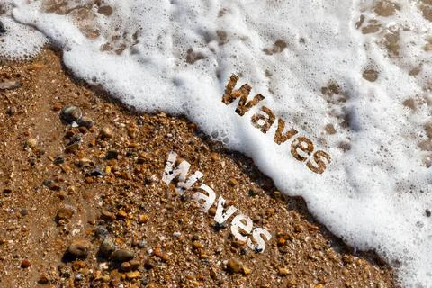 Waves text cut out on pebble beach and lapping waves Stock Photos