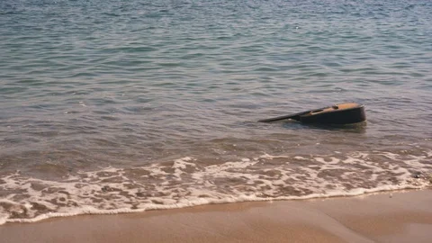 Waves throw guitar ashore or empty sandy wild beach. Tide brings the guitar Видео 126941430