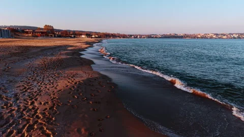 Waves touch the sandy beach as dawn breaks. The sky shows soft colors and the Stock Footage 324635515
