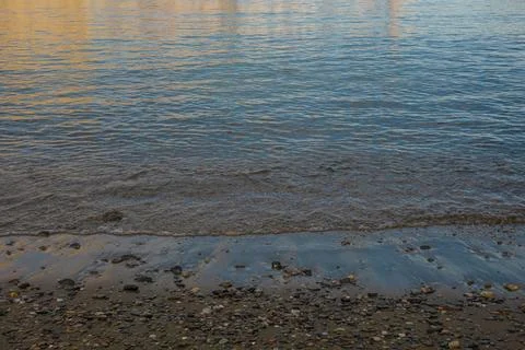 Waves touch the sandy shore as daylight fades into twilight Stock Photos