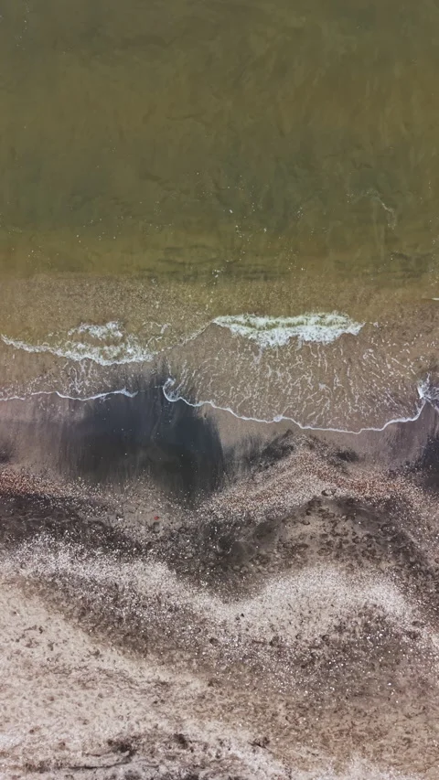 Waves touch the shore at a sandy beach during a quiet day with clear waters and Stock Footage 337907157