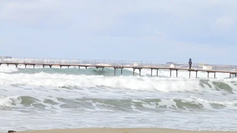 Waves under the pier in the Black Sea, at Anapa Beach. People walking on pier Stock Footage 99698222