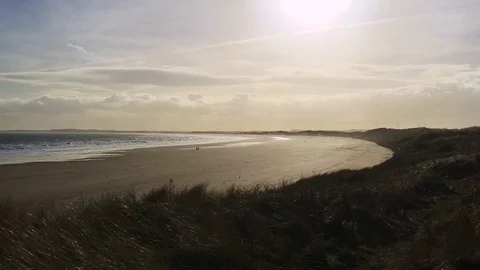 Waves wash in across the sandy beach as the sun sets at twilight 動画素材 73543592