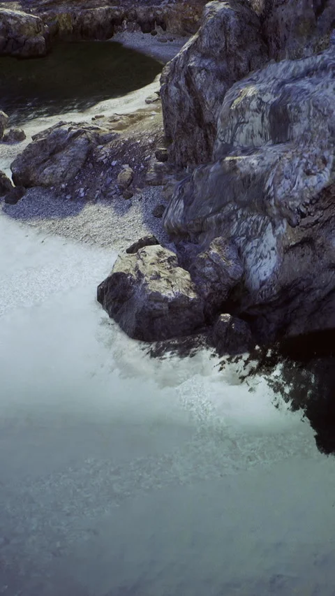 Waves wash against rocks along the shore at a coastal area during sunlight Video stock 342443671