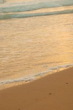Waves wash ashore on sandy beach during evening light near ocean. Waves roll Stock-Fotos