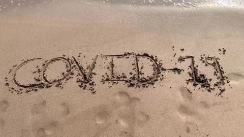 The waves wash away the Covid-19 name on the sand. Pandemic in Mumbai,India. Stock Footage 130519680