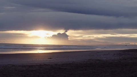 Waves wash up on a beach shore in front of sunset Stock Footage 93749435