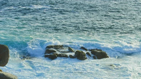 Waves wash over large rock formation at sunset as. birds fly by slow motion Stock-Footage 123565715