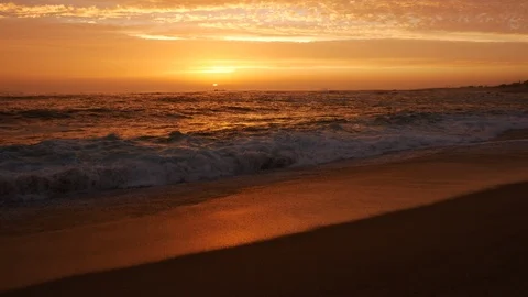 Waves wash over the sandy beach at sunset Stock Footage 111168948