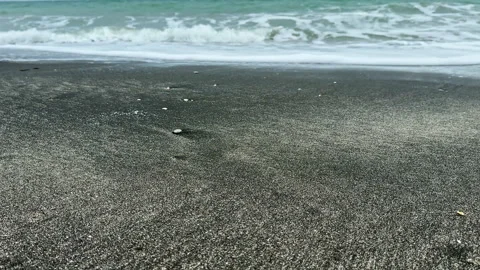 Waves wash over the sandy shore at a beach during daylight hours with gentle Stock Footage 335354380