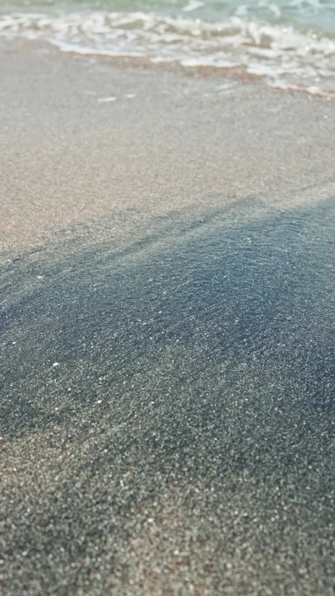 Waves wash over the wet sand at the beach during late afternoon near the ocean, Stock Footage 337882333