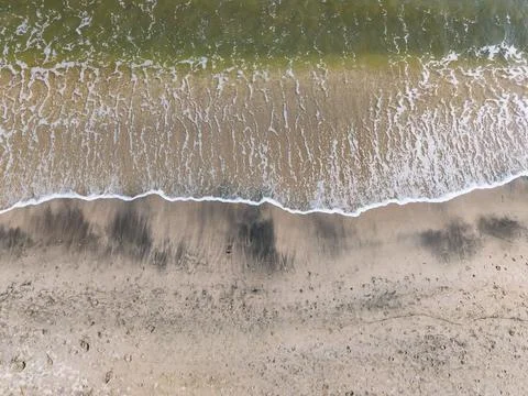 Waves wash onto the shore and create patterns on the sand at the beach duri.. Photos