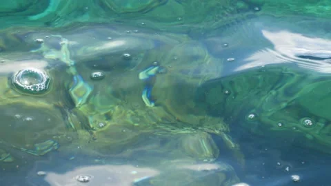 The waves washed over the rocks on the shore. Blue clear water surface Stockbeeldmateriaal 153743132
