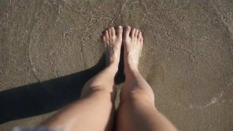 The waves washes woman's feet on beach Stock Footage
