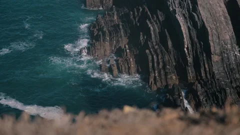 Waves washing against vertical layered sea cliffs, Cabo Sardao, Portugal Stock Footage 346479996