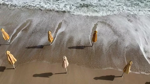 Waves washing away empty beachwith closedparasols. Stock Footage 163063894