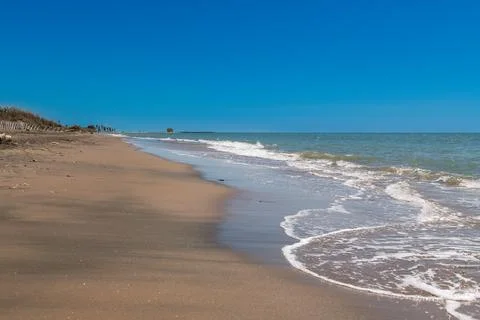 Waves washing onto empty sandy beach shoreline 库存照片