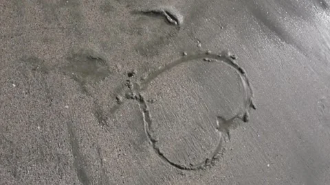 Waves washing out a heart on the beach Stock Footage 243930341