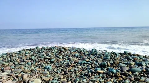 Waves Washing Over a Colorful Pebble Stone Beach Under a Clear Blue Sky 스톡 동영상 344362006