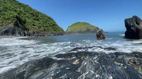 Waves Washing Over A Layered Rock Shelf Below A Tall Dark Sea Stack Stock Footage 342837942