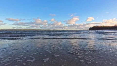 Waves washing over quiet mirrored sandy welsh beach coastline at dawn Stock Footage 325722589