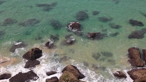Waves washing over rocks from above with blue green water tones Stockbeeldmateriaal 314451773
