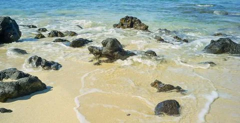 Waves Washing Over Rocks On Sandy Beach Stock Photos