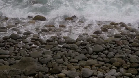 Waves washing over rounded grey boulders on a pebble beach in Higashiizu, Izu 库存影片 345176992