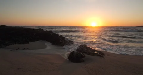 Waves washing over the sandy beach at sunset with sun on the horizon 動画素材 131898365