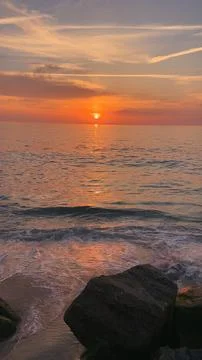 Waves washing onto a sandy beach at sunset Stock Photos