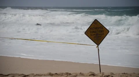 Waves washing up on shore behind warning sign Stock Footage 48032070