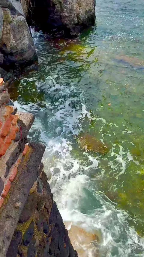 Waves with white foam break against the stone wall and the cliff. Stock Footage 310519814