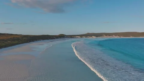 Waves into white sandy shore from a vibrant blue ocean Vídeos de archivo 288802854